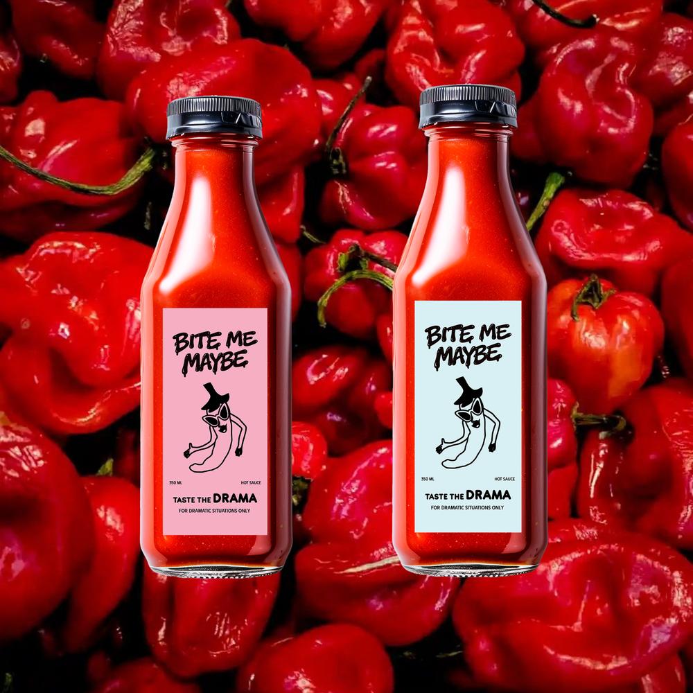 Three bottles of Bite Me Maybe hot sauce nestled in a pile of fresh, bright red chili peppers.